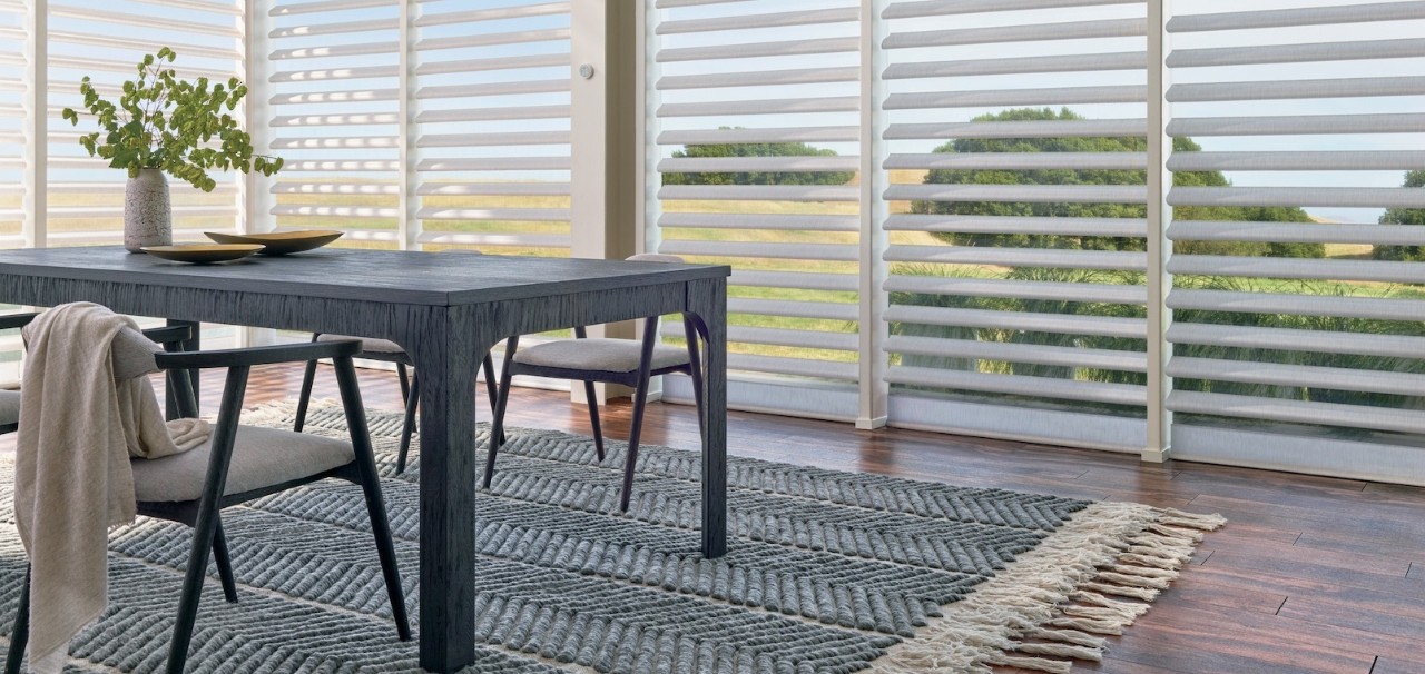 A dining room with a patterned area rug under the dining table and chairs.